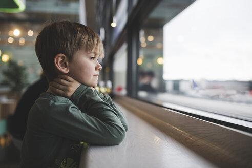 Nachdenklicher Junge lehnt am Tisch am Fenster eines Restaurants - MASF02011
