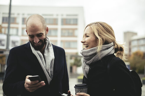 Lächelnde Geschäftsleute mit Smartphones auf dem Bürgersteig in der Stadt - MASF02033