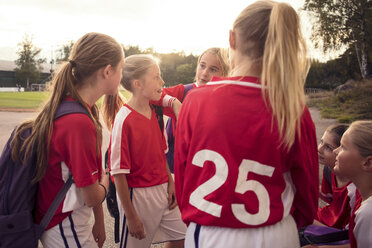 Soccer girls talking on footpath against sky - MASF02049