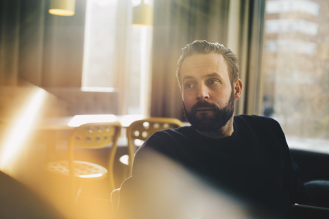 Thoughtful businessman sitting in brightly lit office stock photo