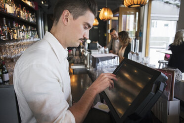 Seitenansicht eines männlichen Besitzers, der die Kasse in einem Restaurant bedient - MASF02063