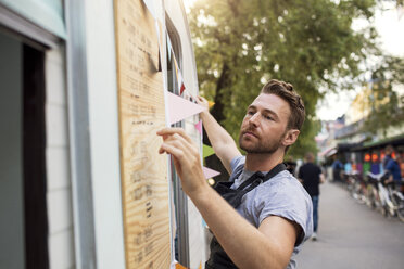 Seitenansicht des Eigentümers, der eine Fahne am Food Truck aufhängt - MASF02067