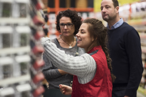 Side view of smiling saleswoman assisting mature couple in hardware store stock photo