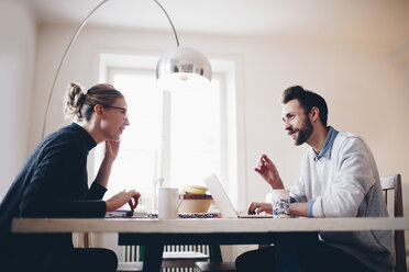 Side view of couple talking while sitting at dining table at home - MASF02091