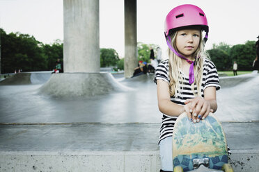 Porträt eines Mädchens mit Skateboard, das im Park sitzt - MASF02118