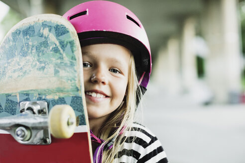 Porträt eines glücklichen Mädchens mit Skateboard im Park - MASF02119