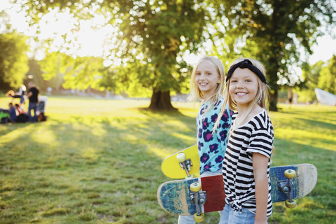 Porträt von lächelnden Freunden mit Skateboards in einem öffentlichen Park, lizenzfreies Stockfoto