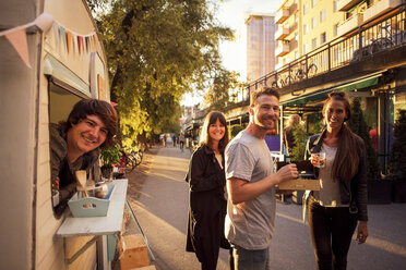 Portrait of happy customers and food truck owner on street - MASF02131