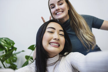 Portrait of happy female bloggers clenching teeth in creative office - MASF02132