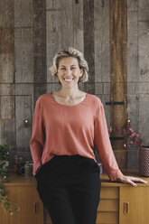Porträt einer lächelnden Geschäftsfrau, die sich auf ein Sideboard vor einer Holzverkleidung in einem tragbaren Büro-LKW stützt - MASF02140