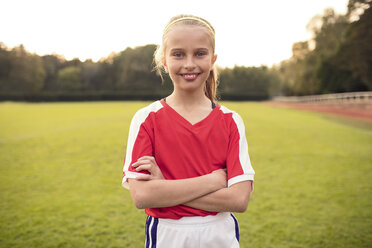 Portrait of happy female athlete standing with arms crossed on soccer field - MASF02150