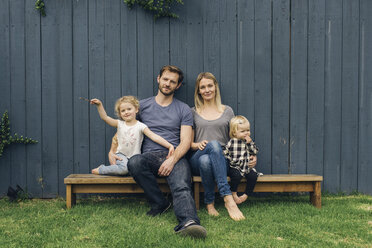 Portrait of happy parents and children sitting on seats against fence at yard - MASF02154