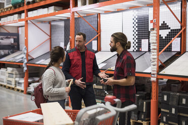 Salesman discussing with couple by shelves at hardware store - MASF02174