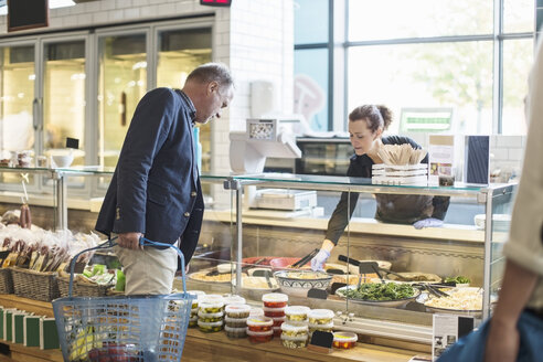 Verkäuferin hilft reifem Mann beim Kauf von Lebensmitteln im Supermarkt - MASF02176