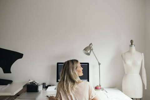 Rückansicht eines weiblichen Designers, der zu Hause einen Computer benutzt, lizenzfreies Stockfoto