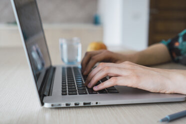 Nahaufnahme einer Frau zu Hause mit Laptop auf dem Tisch - KKAF00918