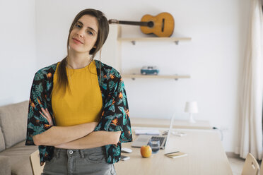 Portrait of smiling young woman at home with guitar on shelf - KKAF00921
