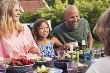 Playful man sitting with girls at dining table in back yard - MASF02198