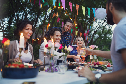 Multiethnische Freunde genießen eine Mahlzeit im Hinterhof bei einer Gartenparty, lizenzfreies Stockfoto