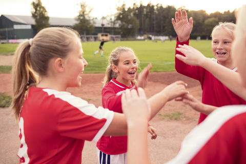 Verspielte Fußballspielerinnen stehen vor dem Feld, lizenzfreies Stockfoto