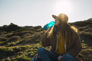 Italien, Sardinien, Frau auf einer Wandertour macht eine Pause und trinkt aus einer Wasserflasche - KKAF00936