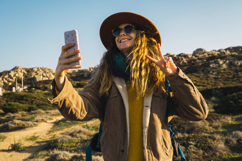 Italien, Sardinien, glückliche Frau auf einem Wanderausflug, die ein Selfie macht, lizenzfreies Stockfoto