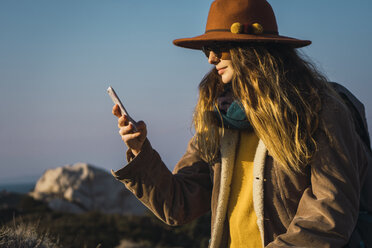 Italien, Sardinien, Frau auf Wandertour schaut auf Handy - KKAF00948