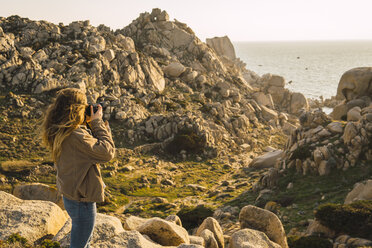 Italien, Sardinien, Frau auf Wanderschaft beim Fotografieren an der Küste - KKAF00956