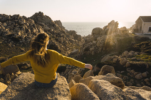 Italien, Sardinien, Frau auf Wanderschaft, sitzend auf einem Felsen an der Küste - KKAF00958