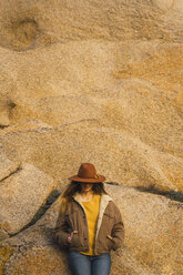 Frau mit Hut lehnt an einer Felswand - KKAF00967