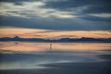 Silhouette einer Person, die auf den Bonneville Salt Flats vor einem bewölkten Himmel steht - CAVF35575