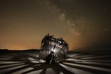 Beleuchtetes Peter-Iredale-Schiff auf Sand vor nächtlichem Sternenhimmel - CAVF35626