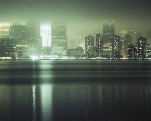 River by illuminated city during foggy weather - CAVF35664