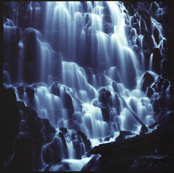 Majestätischer Blick auf einen Wasserfall über Felsformationen in der Abenddämmerung - CAVF35665