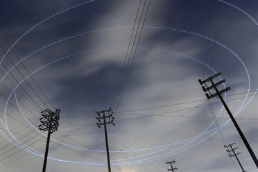 Low angle view of light trails over electricity pylons - CAVF35671