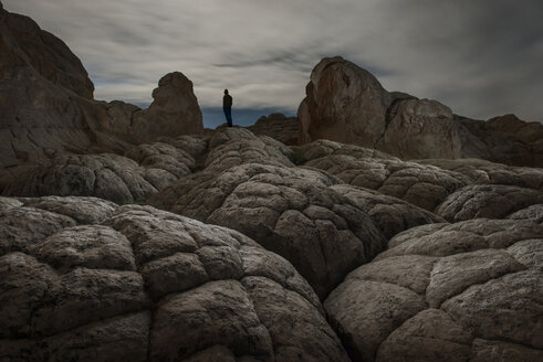 Niedriger Blickwinkel des Mannes auf Felsformationen gegen bewölkten Himmel stehend - CAVF35681