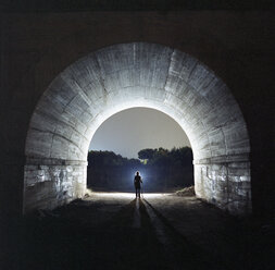 Silhouette man standing in tunnel at dusk - CAVF35692