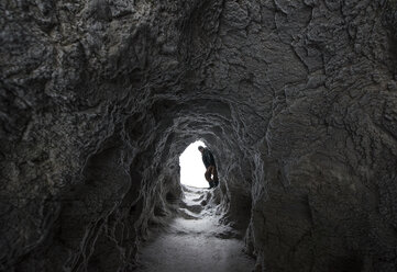 Hiker standing in entrance of cave at Icefields Parkway - CAVF35756