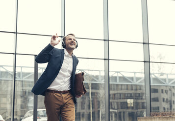 Happy businessman listening to music with headphones - UUF13269