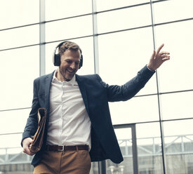 Happy businessman listening to music with headphones - UUF13270
