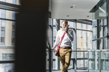 Businessman in office building using smartphone - UUF13281