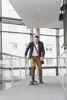 Geschäftsmann fährt Skateboard auf Büroetage - UUF13288