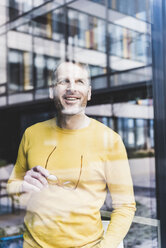 Happy casual businessman looking out of window - UUF13316