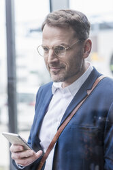 Portrait of confident businessman holding smartphone - UUF13319