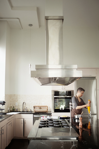 Frau hält Zuckergussbeutel, während sie in der Küche steht, lizenzfreies Stockfoto