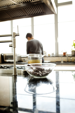 Rückansicht einer Frau beim Kochen in der Küche zu Hause, lizenzfreies Stockfoto