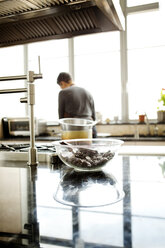 Rückansicht einer Frau beim Kochen in der Küche zu Hause - CAVF35806