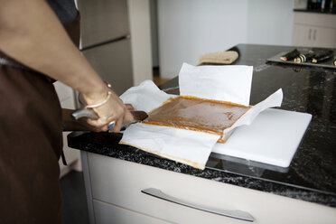 Ausgeschnittenes Bild einer Frau, die Lebensmittel für die Zubereitung eines Desserts zu Hause schneidet - CAVF35807