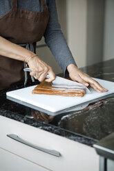 Mittelteil einer Frau, die Lebensmittel für die Zubereitung eines Desserts zu Hause schneidet - CAVF35808