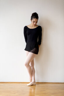 Frau schaut nach unten, während sie im Ballettstudio an der Wand steht - CAVF35875